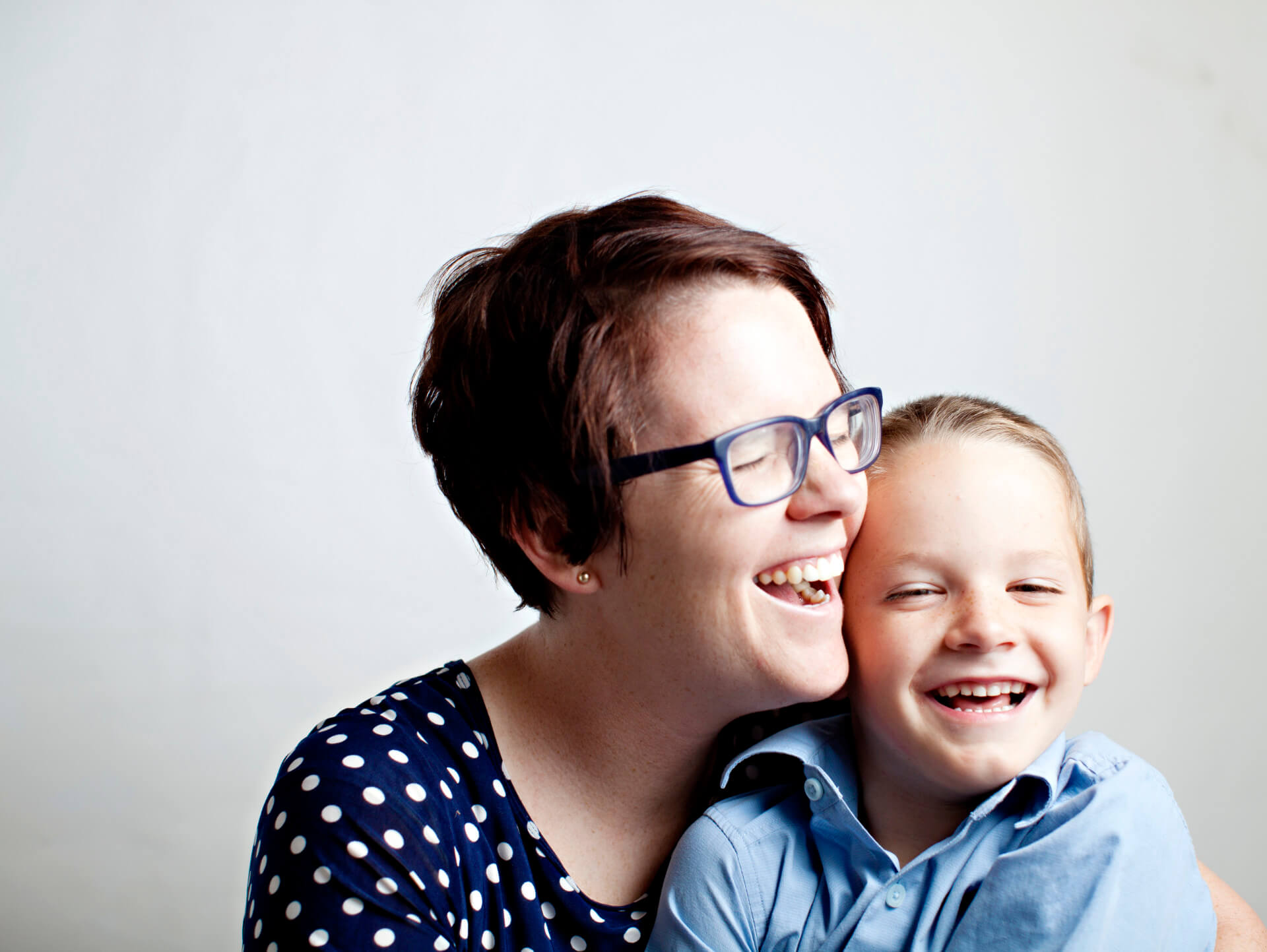 Lachende Mutter hält ihr lachendes und glückliches Kind im Arm.